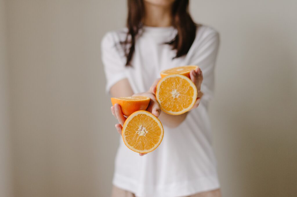 Mulher segurando fruta com vitamina C.