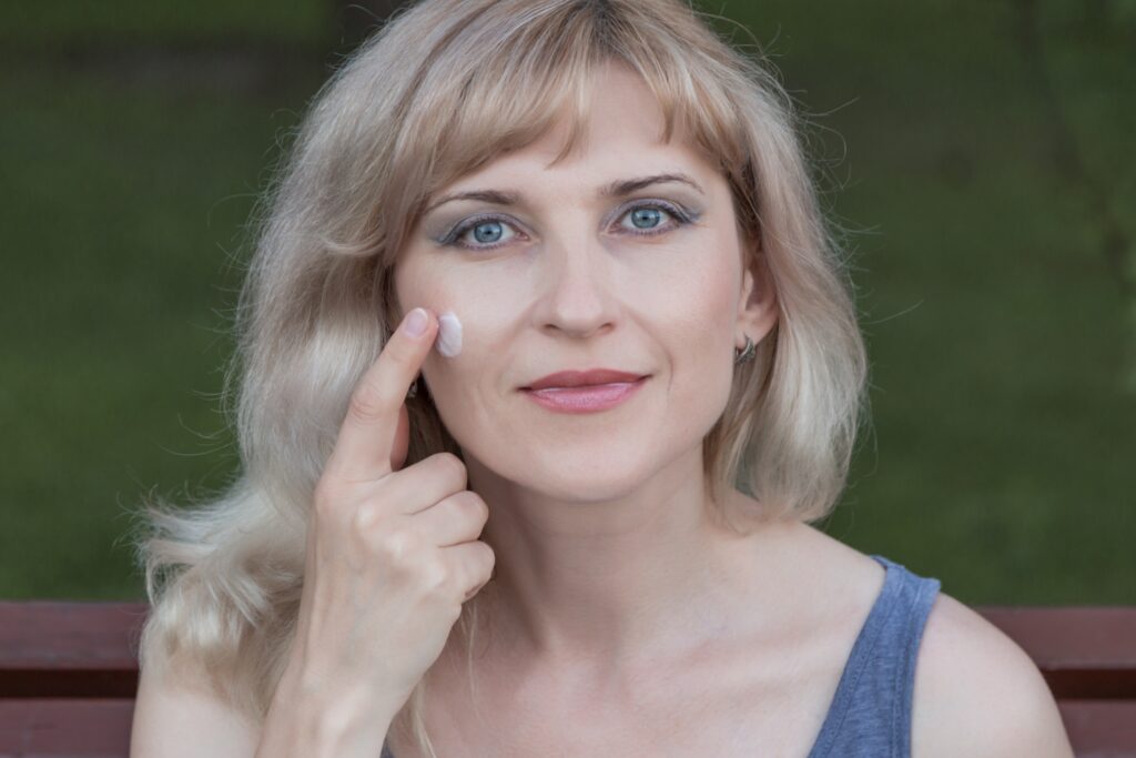 Mulher passadno creme no rosto, com o dedo indicador