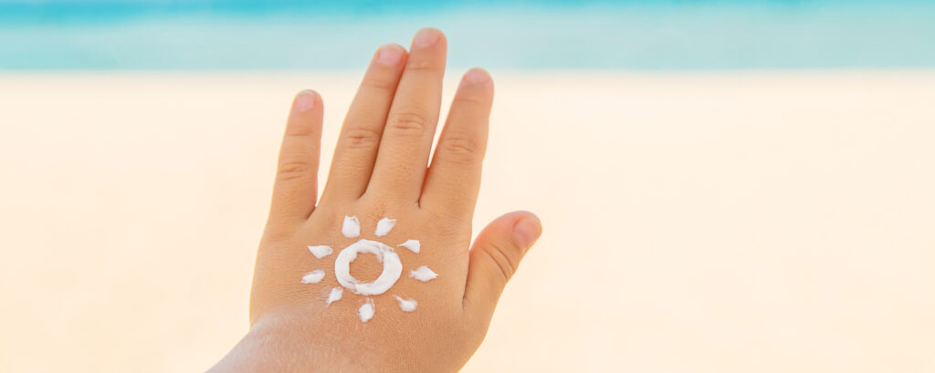 mão de criança com proteção solar e desenho de sol